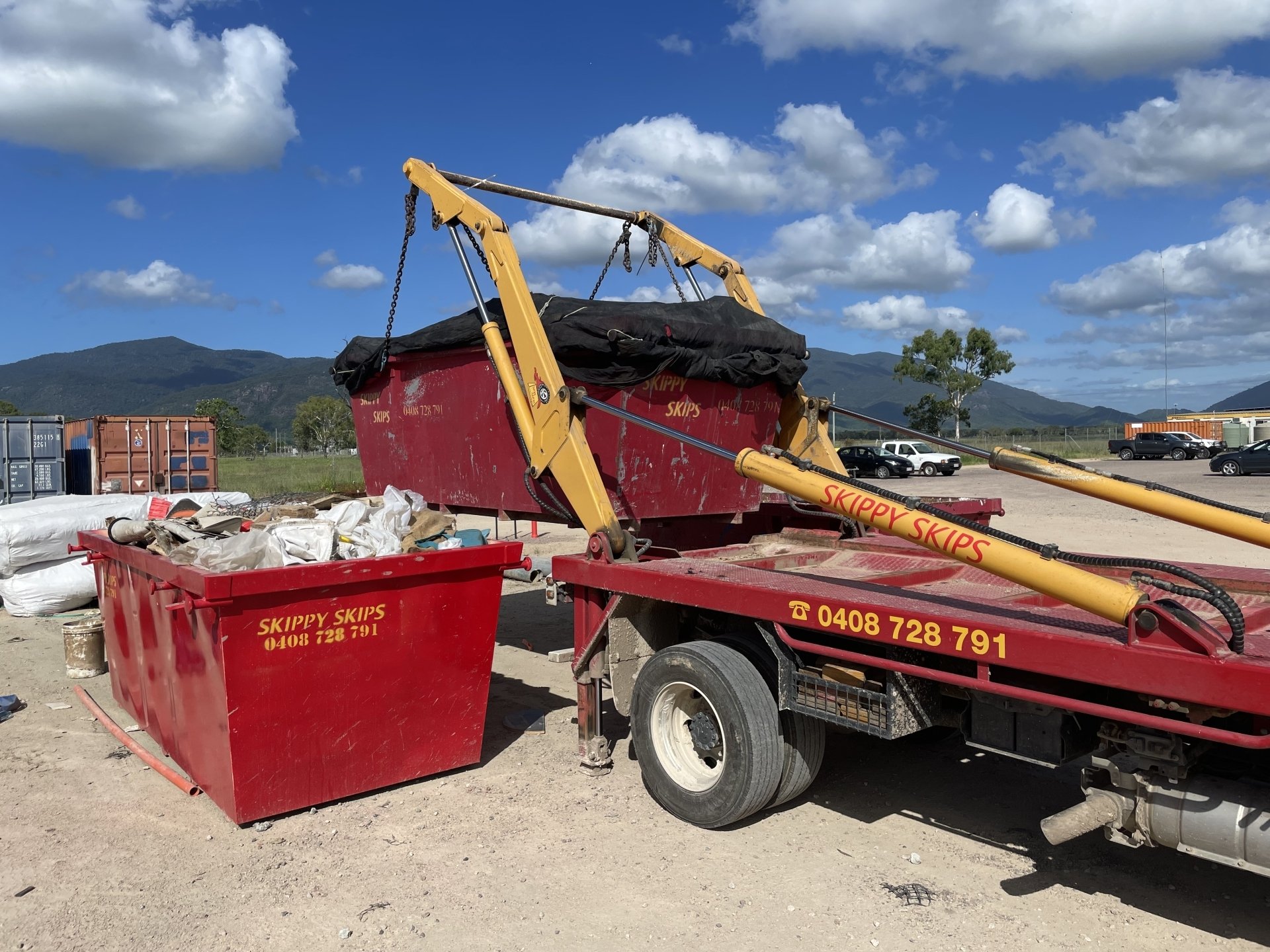 Skippy Skips hydraulic lift truck lifting a red skip bin